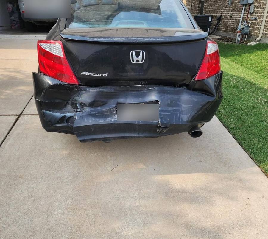 Black Honda Accord with a torn and dented rear bumper before repair