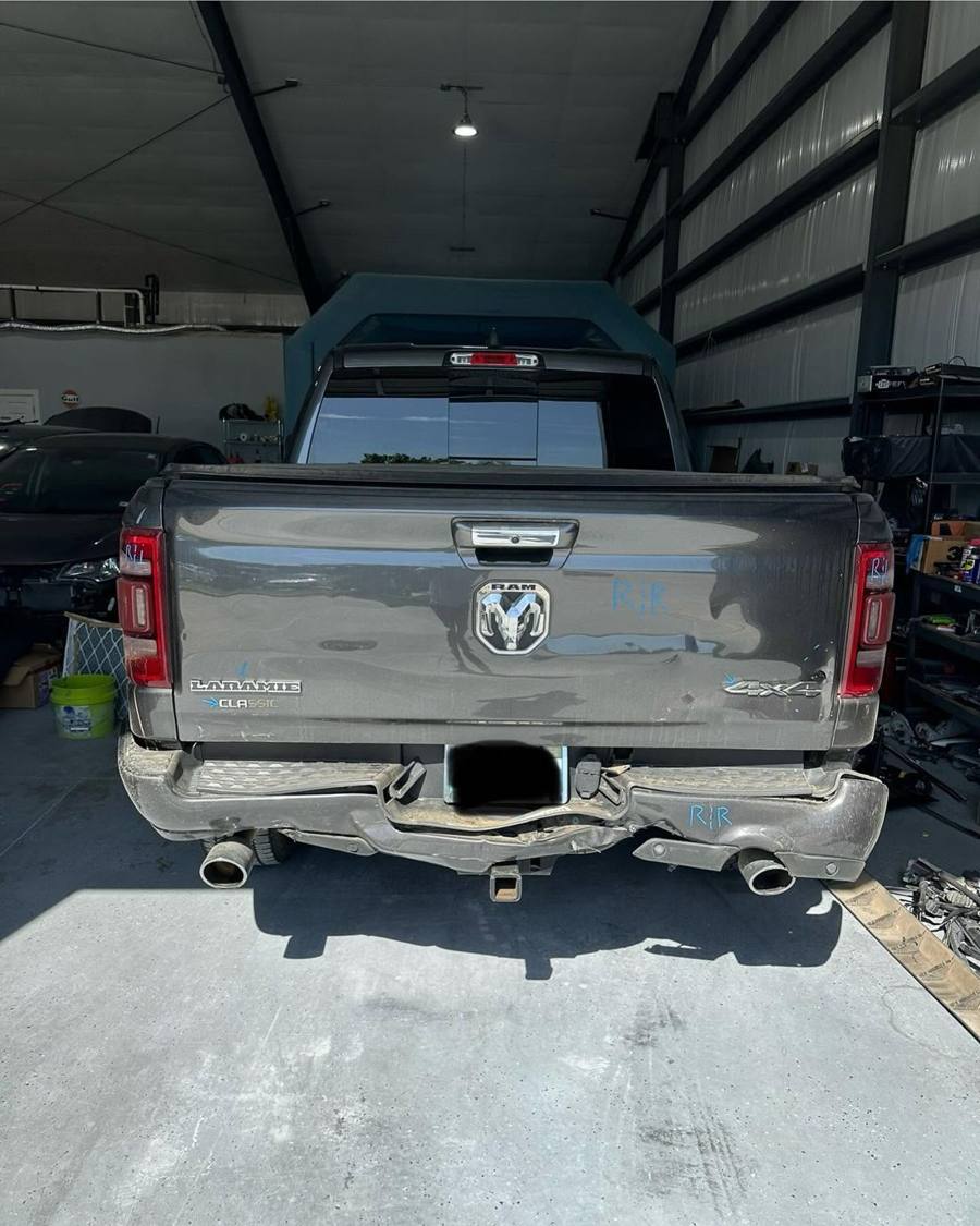 Gray Ram 1500 with a crushed rear bumper inside the Collision Kings shop