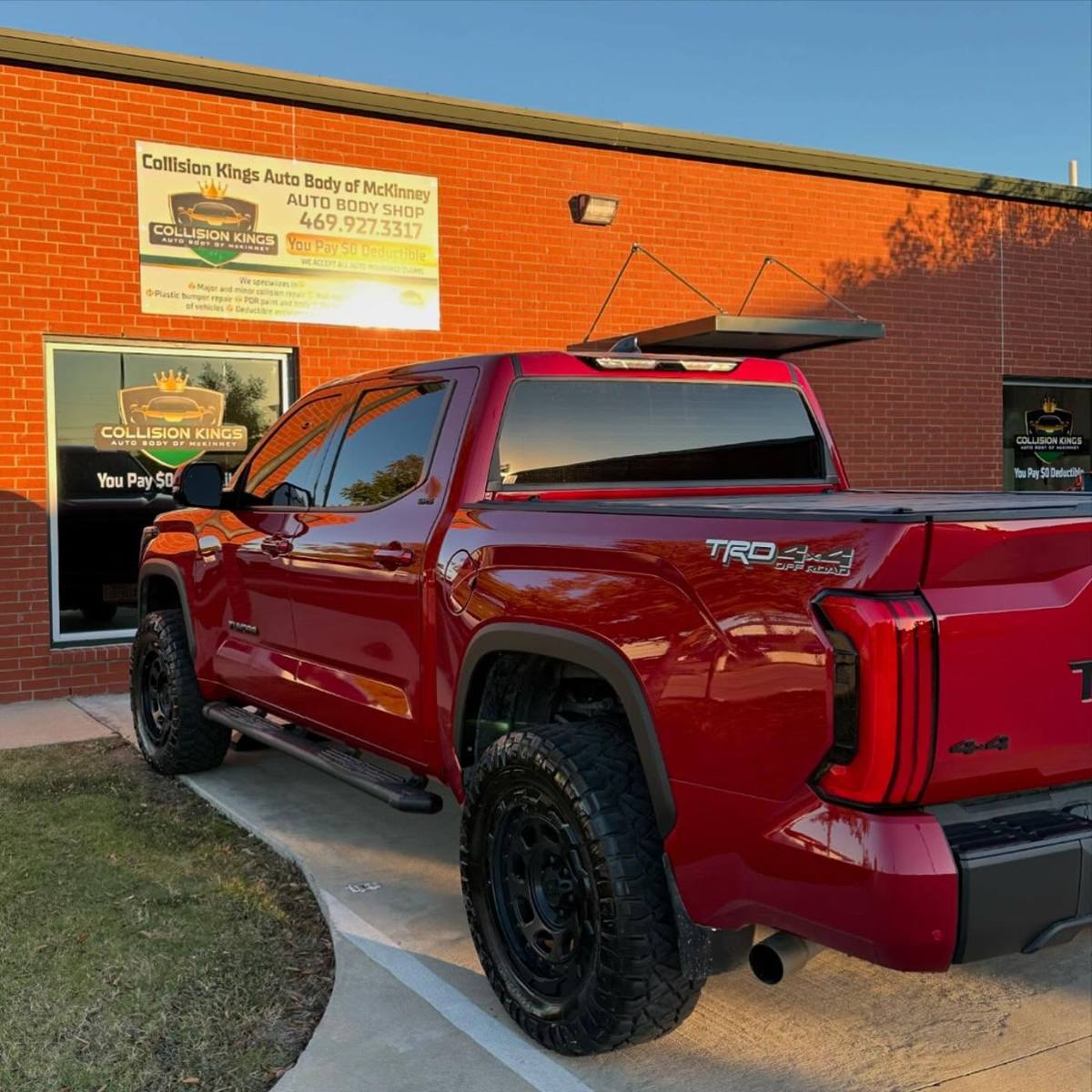 Red Toyota Tundra TRD after collision repair, parked outside the Collision Kings shop in McKinney at sunset