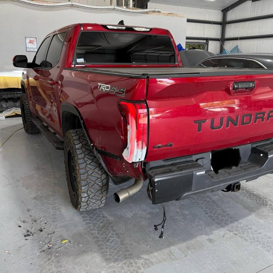 Red Toyota Tundra before repair, with rear quarter panel, taillight, and bumper damage